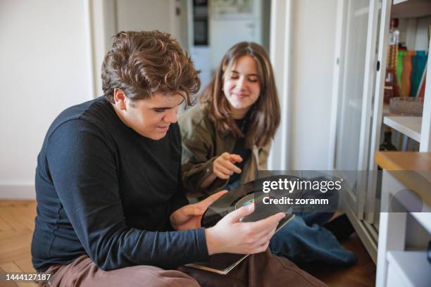 dos adolescentes mirando vinilos de larga duración en casa - lp fotografías e imágenes de stock