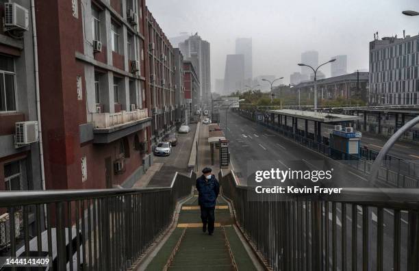 Man wears a mask to prevent the spread of COVID-19 as he walks alone up an overpass next to a nearly empty street near the Central Business District...