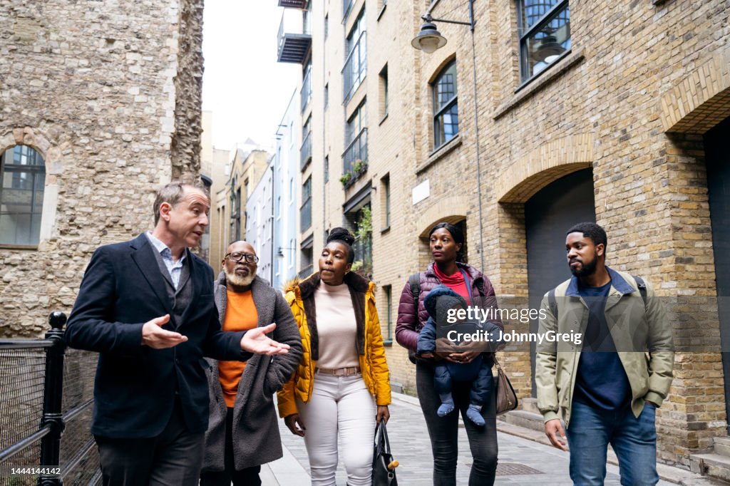 Londoner Reiseführer, der Touristen durch Ruinen in der Clink Street führt