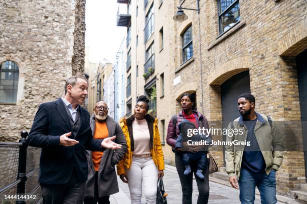 guía de londres guiando a los turistas a través de las ruinas de clink street - historia social fotografías e imágenes de stock