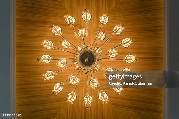 low angle view of illuminated light hanging from wooden ceiling - fitting stockfoto's en -beelden