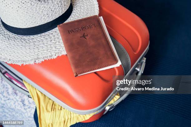 top view of a suitcase full of clothes ready to travel with a passport placed on top of it. - passport open stock pictures, royalty-free photos & images