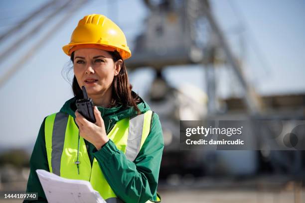 portrait of a female engineer using walkie-talkie at industrial facility - cement mixer truck stock pictures, royalty-free photos & images