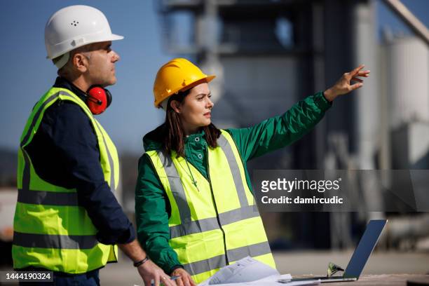 male and female industrial engineers in hard hats discuss new project while using laptop - project manager stock pictures, royalty-free photos & images