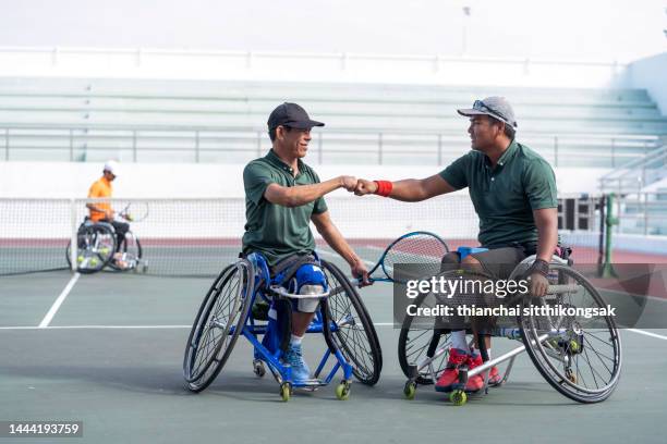 adaptive athletes shaking hands at net after wheelchair tennis match. - wheelchair tennis stockfoto's en -beelden