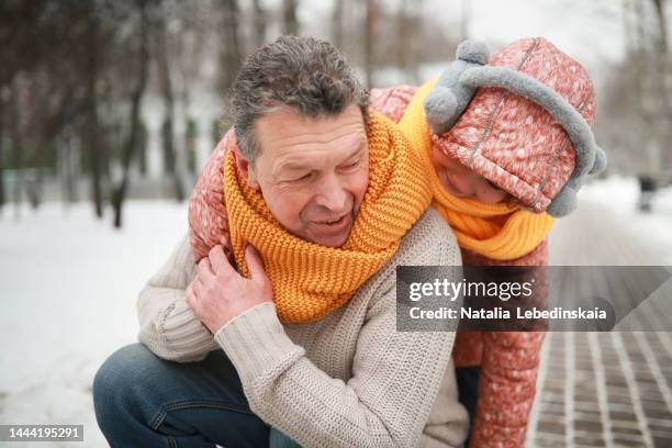 happy schoolgirl girl in jacket with dad hugging in snowy winter - grandfather child snow winter stock-fotos und bilder