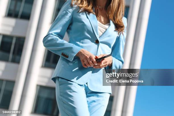 midsection young elegant business woman with smartphone walking at the city center - buste photos et images de collection