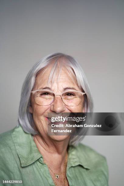 vertical portrait of a happy aged woman with grey hair and casual clothing - happy face glasses stockfoto's en -beelden