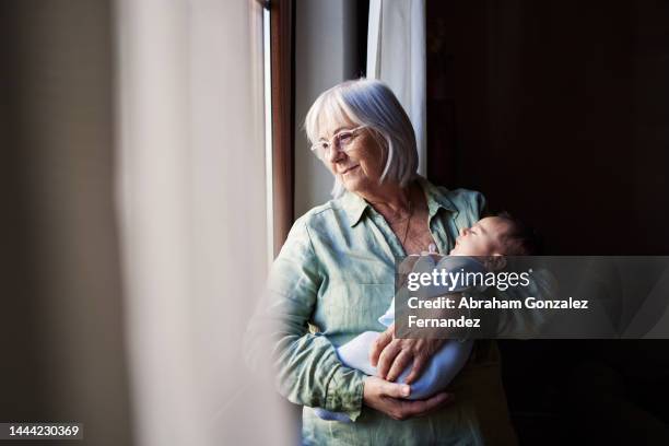 aged woman holding her grandson while looking through the window - pregnant women greeting stockfoto's en -beelden