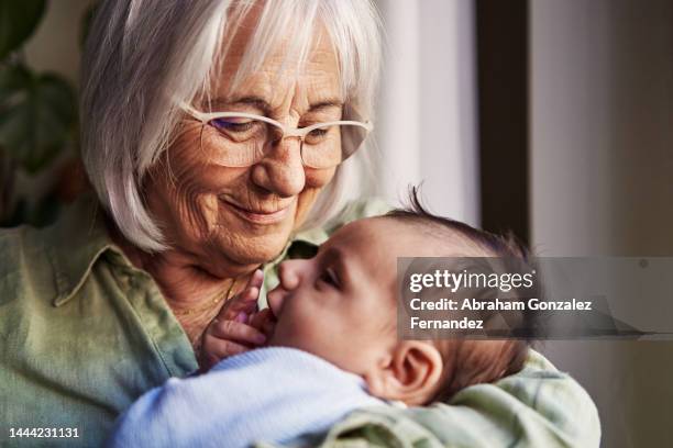 happy grandmother holding her newborn grandchild - granny stockfoto's en -beelden