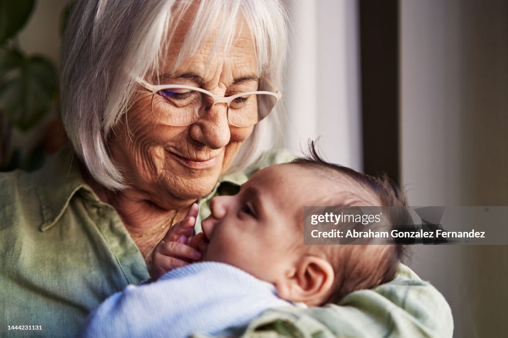 Happy grandmother holding her newborn grandchild