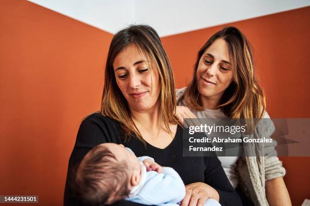 mother holding her child with her sister in the baby's room - monoparental stock-fotos und bilder