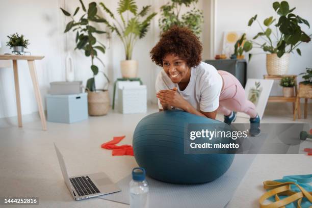 frau, die übungen zu hause macht und online-training beobachtet - pilates ball man stock-fotos und bilder