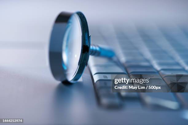 selective focus on magnifying glass on top of computer keyboard,malaysia - vergrößerungsglas stock-fotos und bilder