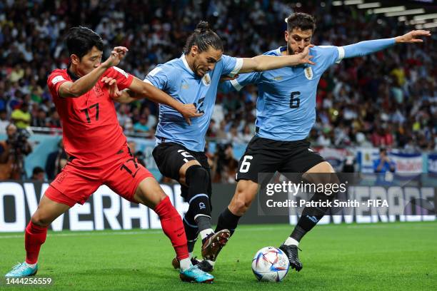 Sangho Na of Korea Republic battles for possession with Martin Caceres and Rodrigo Bentancur of Uruguay during the FIFA World Cup Qatar 2022 Group H...