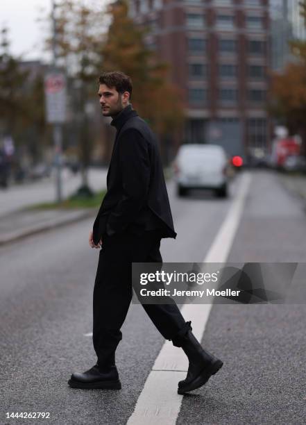 Felix Hartmann wearing a grey Aylin Koenig sweater & suit and black Bottega Veneta boots on November 18, 2022 in Hamburg, Germany.