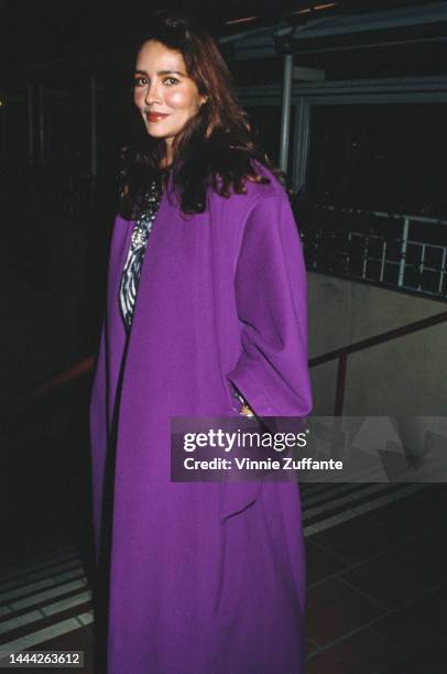 Barbara Carrera attends an event wearing a purple coat, circa 1990s.