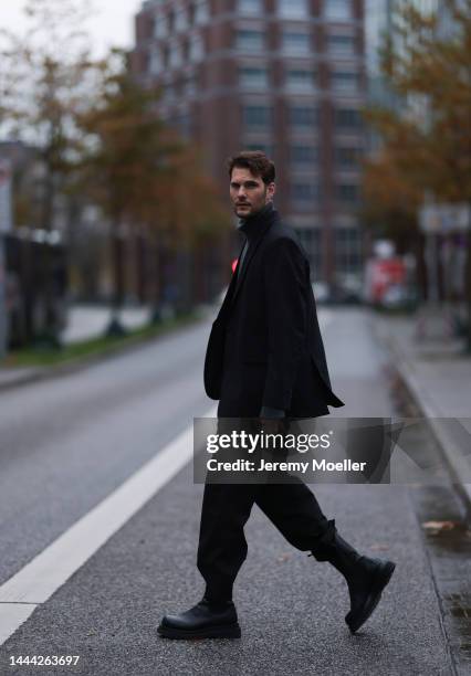 Felix Hartmann wearing a grey Aylin Koenig sweater & suit and black Bottega Veneta boots on November 18, 2022 in Hamburg, Germany.