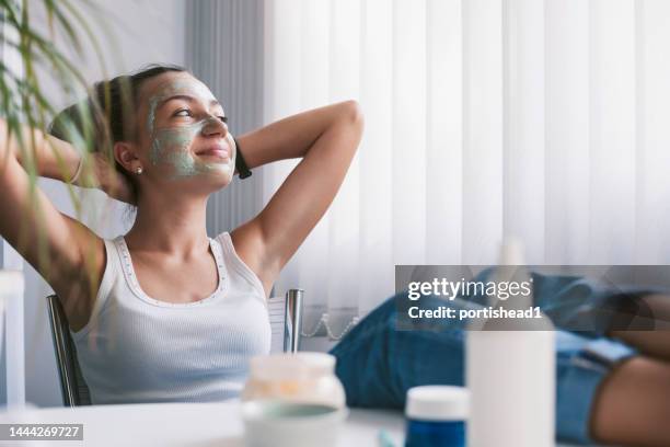 beautiful teenage girl applying face mask at home - pores stockfoto's en -beelden