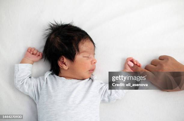 newborn baby securely grasping his mother's finger - mom and baby sleeping stock pictures, royalty-free photos & images