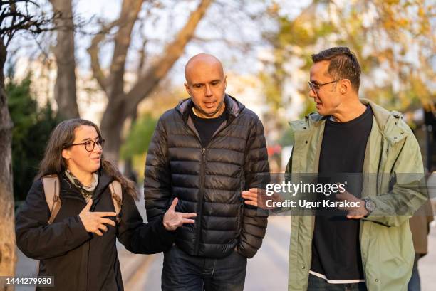 one woman and two men walking together on street - short guy tall woman stock pictures, royalty-free photos & images