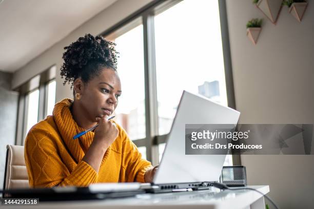 femme noire travaillant à domicile - person on computer photos et images de collection