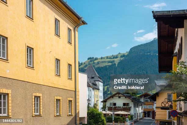 residential buildings of kitzbuhel against green hills and blue sky of tyrol, austria - kitzbühel stockfoto's en -beelden