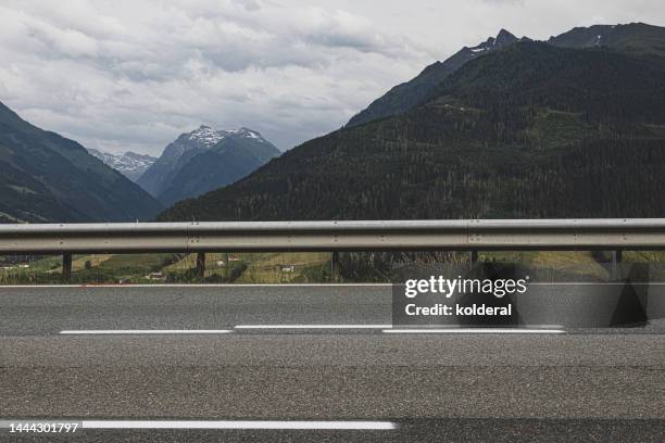 highway asphalt road with distant view of european alps, tyrol, austria - street stock-fotos und bilder