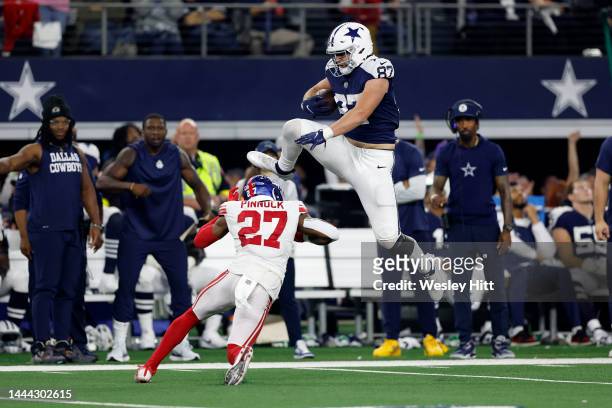Jake Ferguson of the Dallas Cowboys jumps over Jason Pinnock of the New York Giants during the second half at AT&T Stadium on November 24, 2022 in...