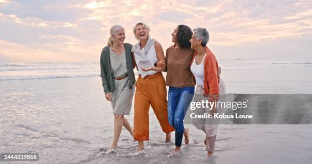 beach holiday, laughing and senior friends walking in the water during retirement travel in bali. summer, smile and diversity with happy elderly women on a walk during group vacation by the ocean - mulheres maduras imagens e fotografias de stock