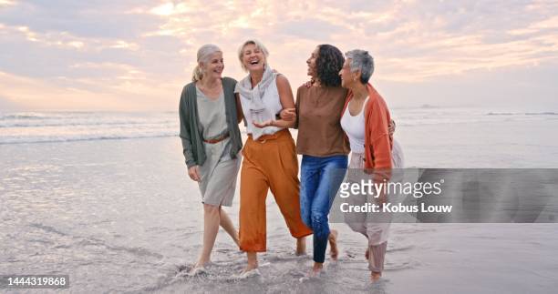 beach holiday, laughing and senior friends walking in the water during retirement travel in bali. summer, smile and diversity with happy elderly women on a walk during group vacation by the ocean - friends smile bildbanksfoton och bilder