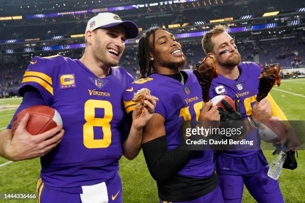 Kirk Cousins, Justin Jefferson and Adam Thielen of the Minnesota Vikings eat turkey legs on the field after defeating the New England Patriots at...