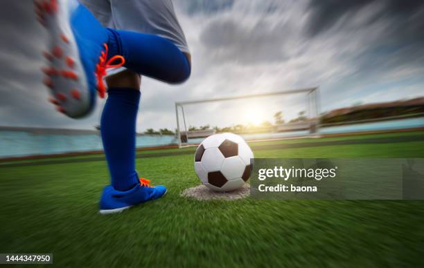 sezione bassa dei piedi del ragazzo che calciano un pallone da calcio - hitting foto e immagini stock