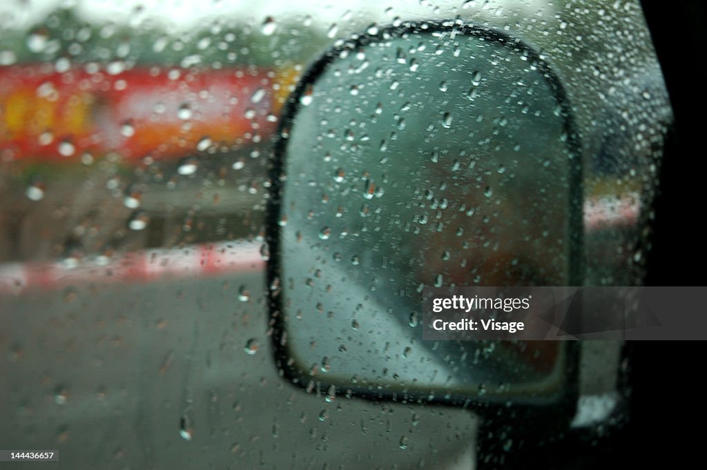 View of a rear view mirror of a car on a rainy day