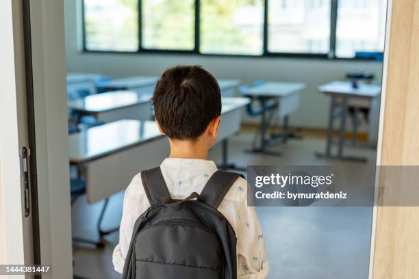 colegial con mochila entrando al aula - boy sad fotografías e imágenes de stock