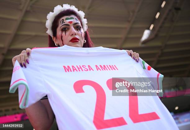 Fans hold up a shirt with the name of Mahsa Amini and a flag advocating for women's rights prior to the FIFA World Cup Qatar 2022 Group B match...