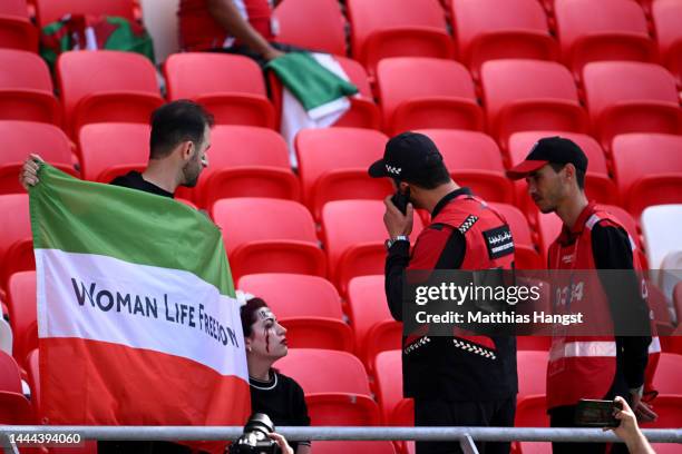 Security staff speak with fans holding up a shirt with the name of Mahsa Amini and a flag advocating for women's rights prior to the FIFA World Cup...