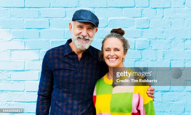 portrait of man and woman next to blue wall - old hipster stock-fotos und bilder