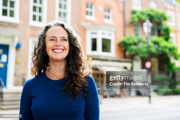 woman looking up, smiling, urban area - testimonial stockfoto's en -beelden