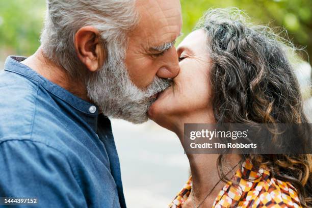 woman and man sharing a kiss - kussen stockfoto's en -beelden