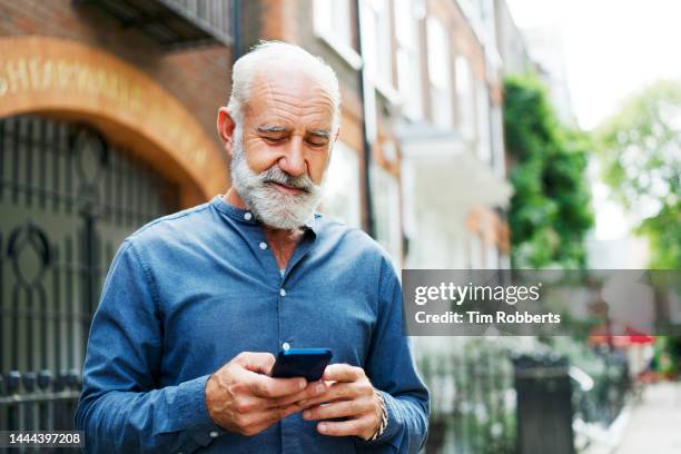 man using smart phone, smiling - senior men stock pictures, royalty-free photos & images