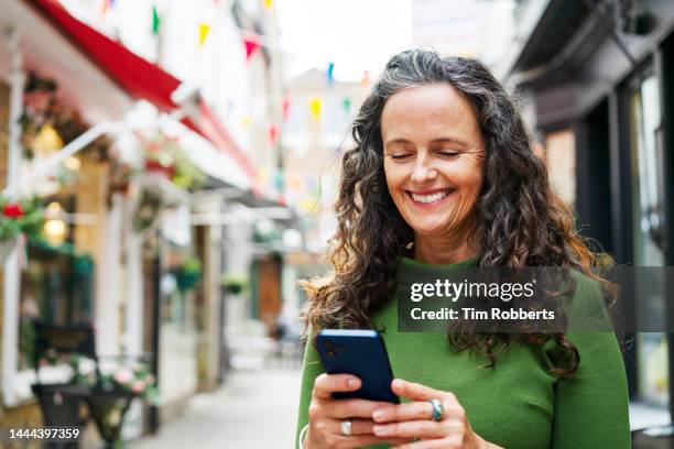 woman using smart phone in town - one woman only shopping stock pictures, royalty-free photos & images