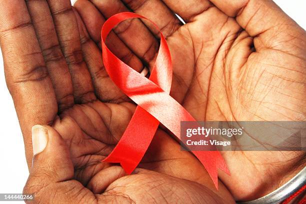 top angle shot of the human hand holding a red ribbon, the aids symbol - レッドリボン ストックフォトと画像