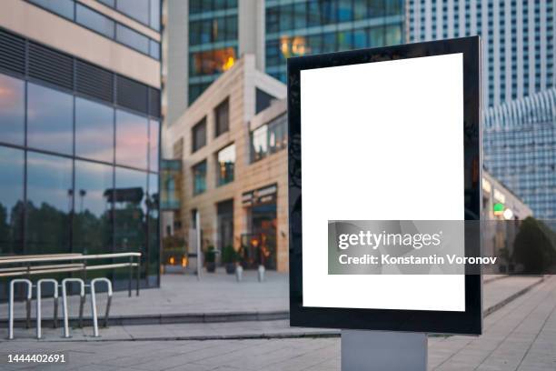 blank city format (lightposter, citylight) banner pylon in the modern city mockup. shopping centre, shop windows, bike parking, high-rise business buildings on blurred background. outdoor advertising - citylight mockup imagens e fotografias de stock