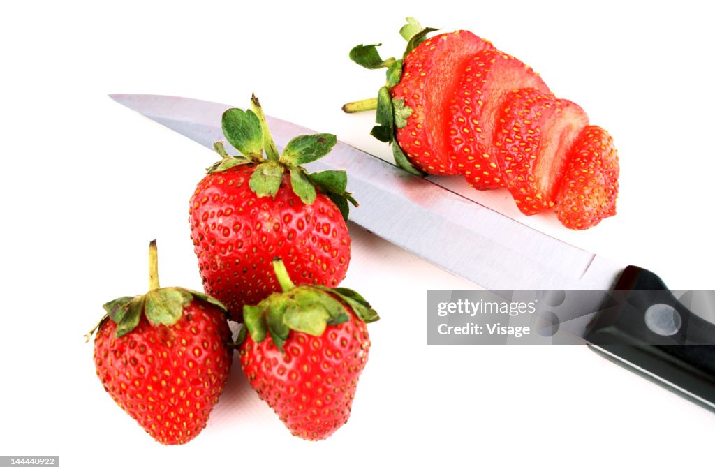 A strawberry, slices and knife