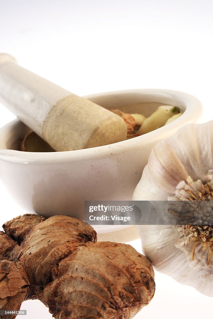 Ginger and garlic by a mortar with pestle