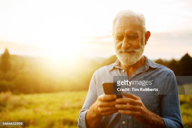 man using smart phone at sunset - distinguished gentlemen with white hair stock pictures, royalty-free photos & images