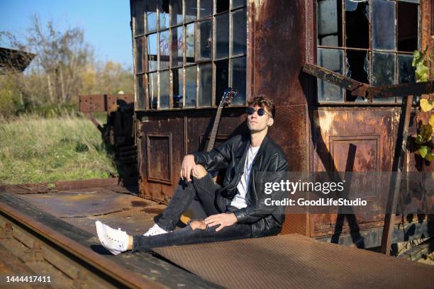 rock guitarist - outdoor guy sitting on a rock stockfoto's en -beelden