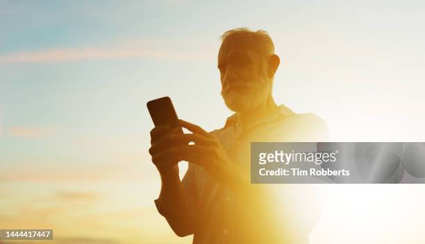 man stood using smart phone with sunset - distinguished gentlemen with white hair stock pictures, royalty-free photos & images