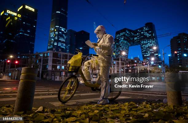 An epidemic control worker who performs nucleic acid tests on people under health monitoring checks a list as she wears a protective suit to prevent...